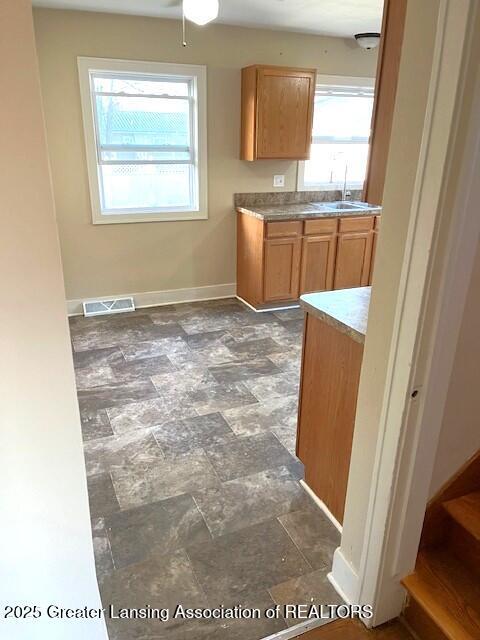 kitchen featuring a sink, baseboards, light countertops, and visible vents