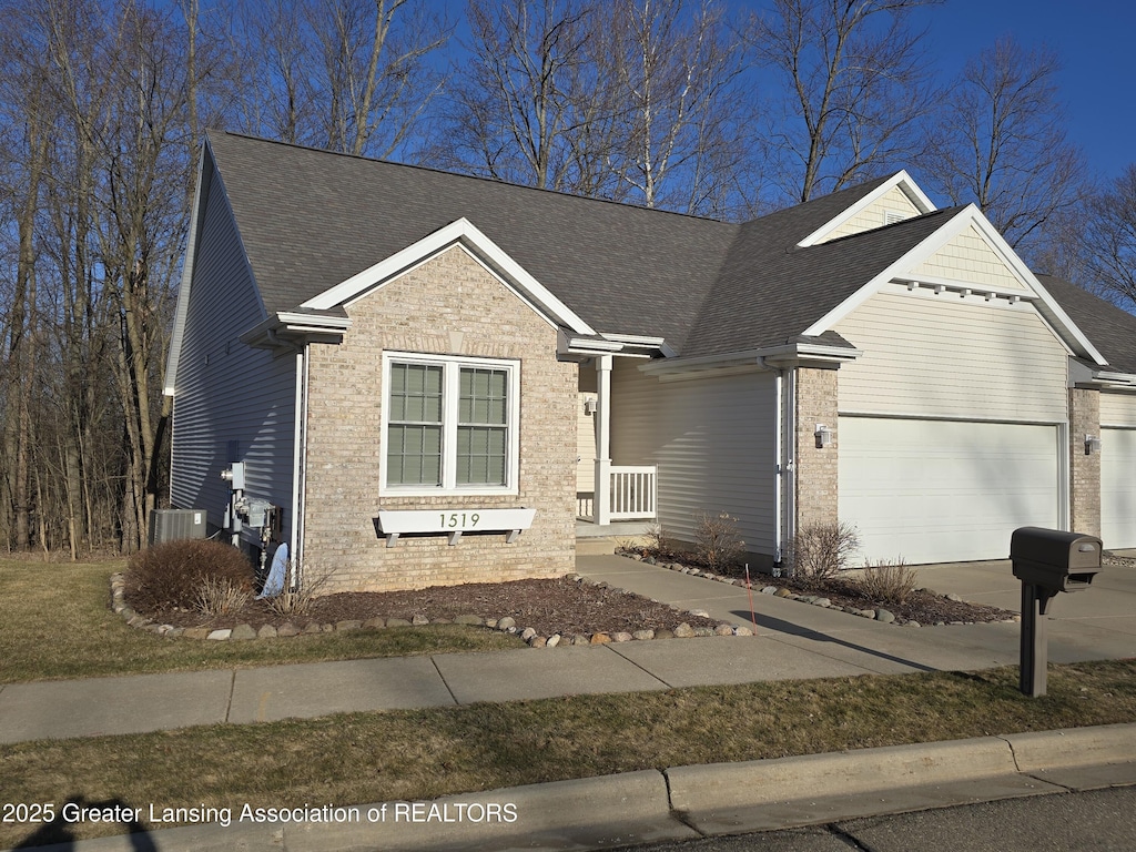 view of front of home featuring brick siding, an attached garage, a shingled roof, and driveway