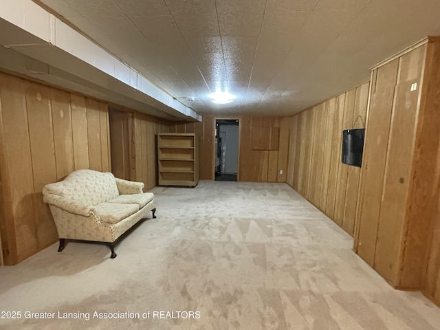 sitting room featuring light carpet and wooden walls