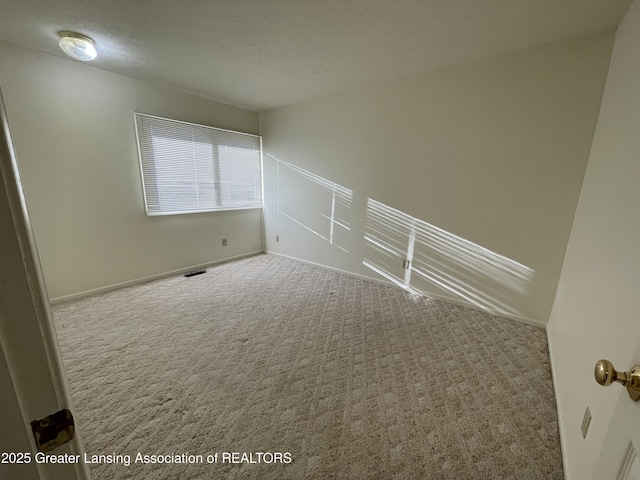 spare room with a textured ceiling, carpet, and visible vents