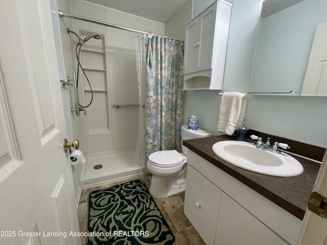 bathroom featuring toilet, a stall shower, and vanity