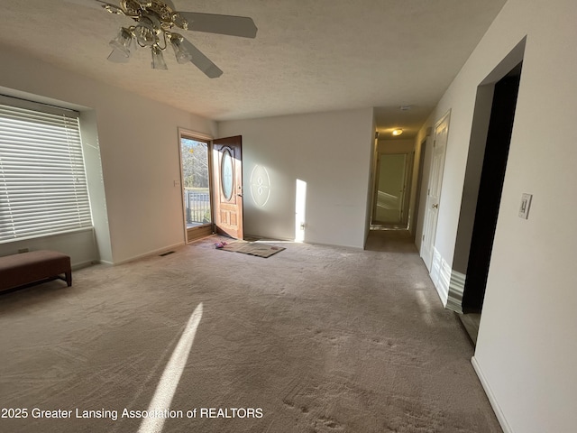 interior space with a textured ceiling, a ceiling fan, and baseboards