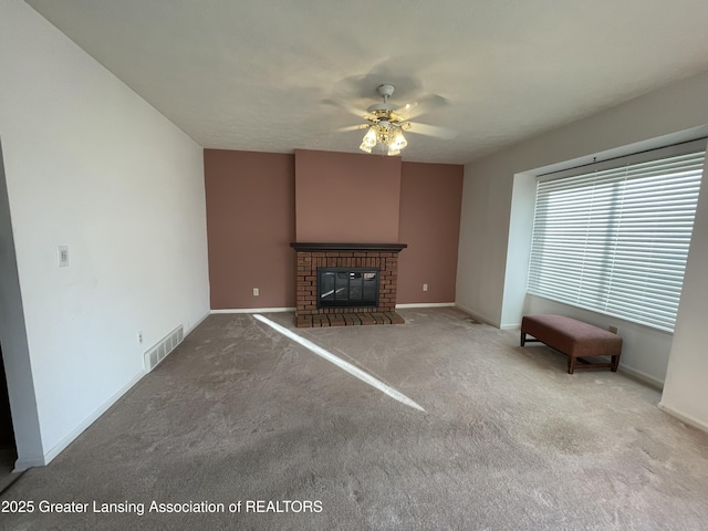 unfurnished living room with visible vents, baseboards, ceiling fan, carpet, and a fireplace