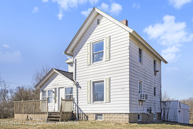 view of front of property with a deck, a chimney, and cooling unit