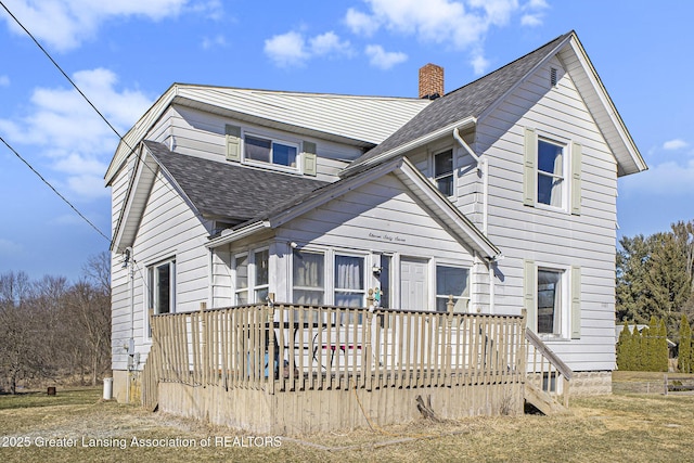 view of front facade featuring roof with shingles, a chimney, and a wooden deck