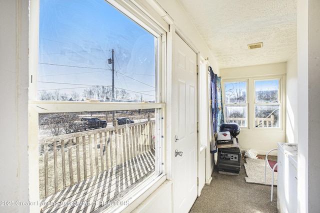 doorway to outside featuring a textured ceiling, carpet, and visible vents