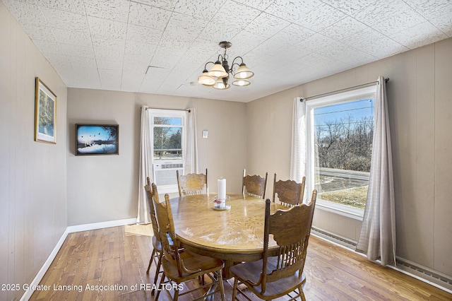 dining area featuring baseboards, a healthy amount of sunlight, an inviting chandelier, and wood finished floors