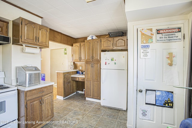 kitchen with brown cabinets, white appliances, and light countertops