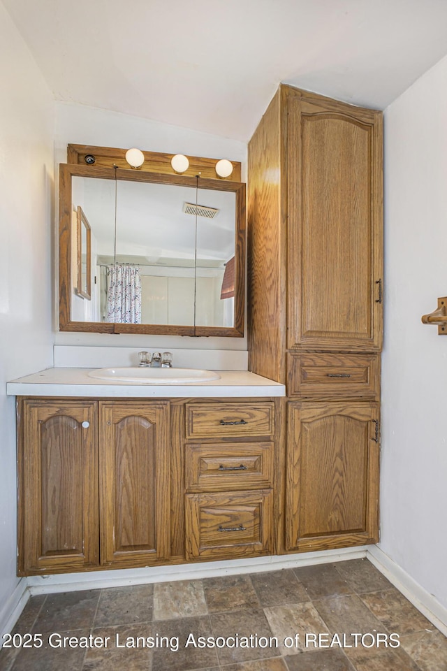 bathroom with stone finish flooring, vanity, and baseboards