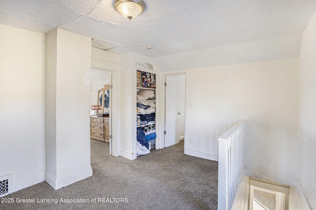 bedroom featuring a textured ceiling, carpet floors, baseboards, vaulted ceiling, and attic access