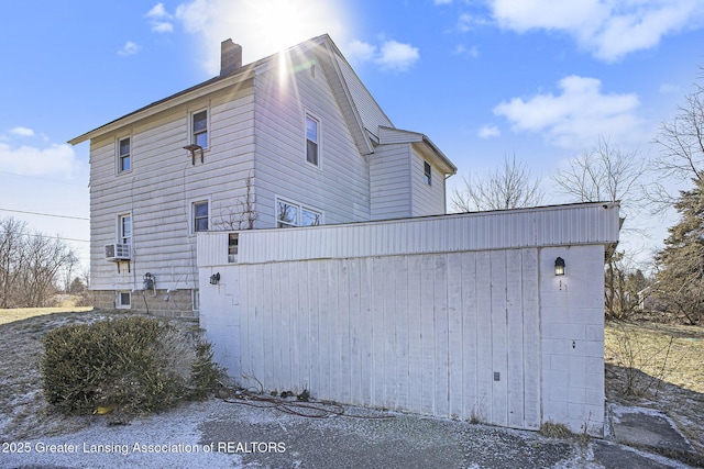 view of side of home featuring a chimney and cooling unit