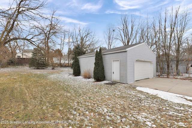 detached garage featuring fence and driveway