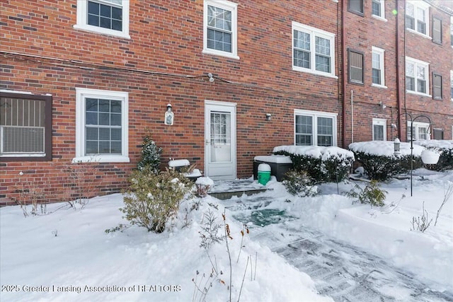 snow covered property entrance with brick siding