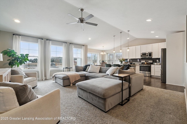 living area featuring lofted ceiling, dark wood-style floors, recessed lighting, and ceiling fan with notable chandelier