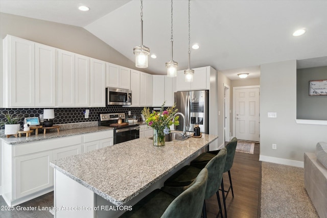 kitchen with lofted ceiling, appliances with stainless steel finishes, backsplash, and white cabinets