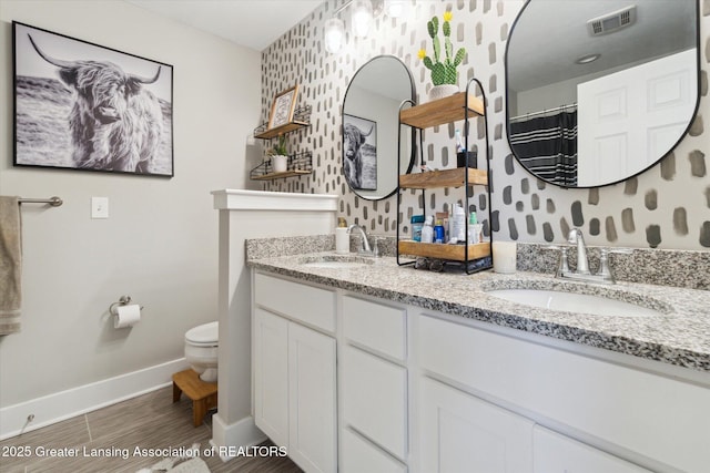 full bathroom with toilet, a sink, visible vents, and baseboards