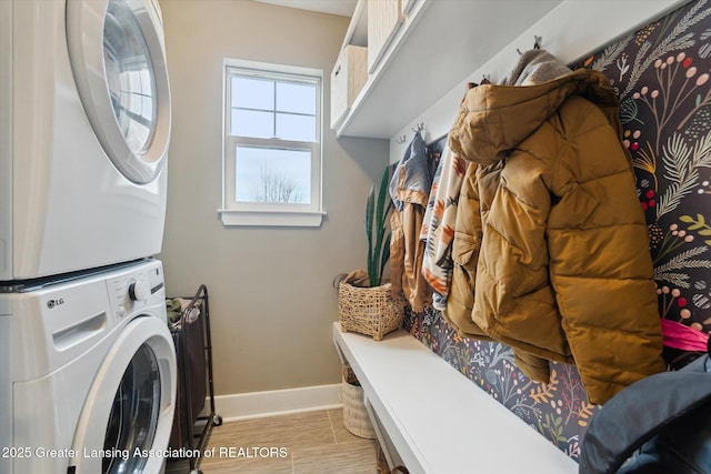 laundry room with laundry area, stacked washer / dryer, light wood-style flooring, and baseboards