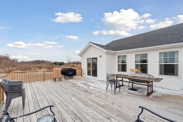 wooden terrace with outdoor dining space and grilling area