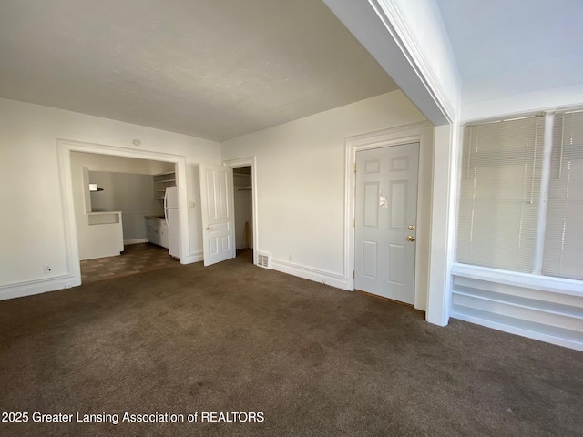 interior space with visible vents, dark carpet, and baseboards