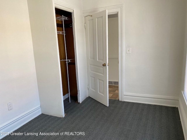 unfurnished bedroom featuring a closet, baseboards, and dark colored carpet