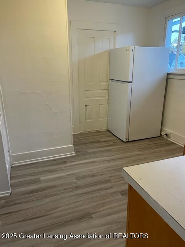 kitchen featuring baseboards, light wood finished floors, and freestanding refrigerator