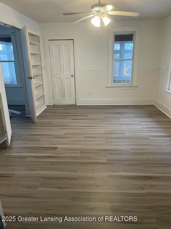 unfurnished bedroom featuring ceiling fan, a closet, baseboards, and wood finished floors