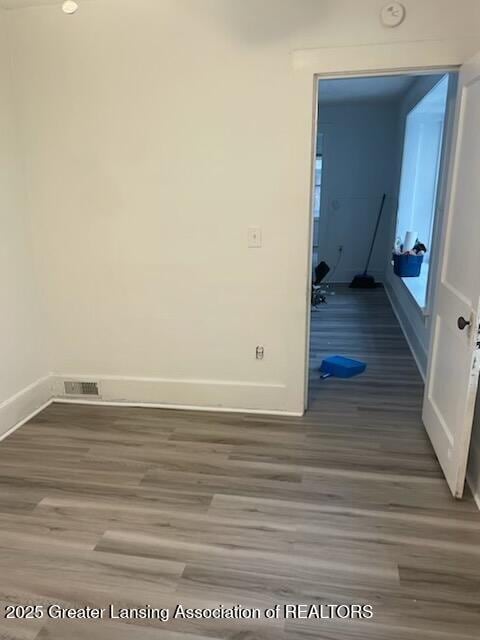 spare room with visible vents, baseboards, and wood finished floors