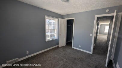 unfurnished bedroom with a closet, a textured ceiling, baseboards, and carpet floors