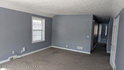 unfurnished room featuring dark colored carpet, baseboards, and a textured ceiling