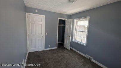 unfurnished bedroom featuring carpet, baseboards, a closet, and a textured ceiling