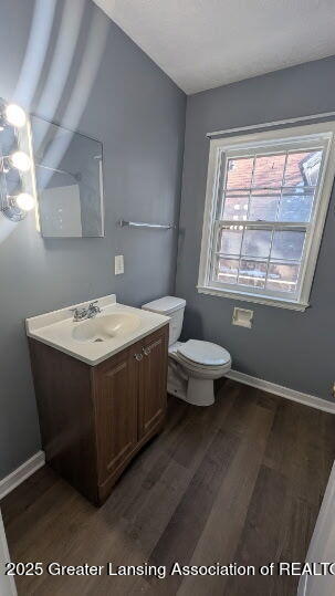 bathroom featuring toilet, vanity, baseboards, and wood finished floors