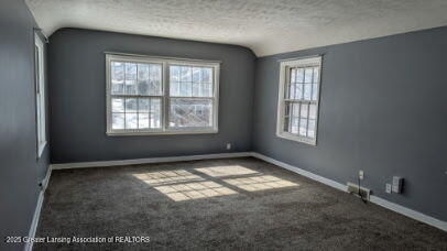 unfurnished room featuring baseboards, a textured ceiling, carpet, and vaulted ceiling