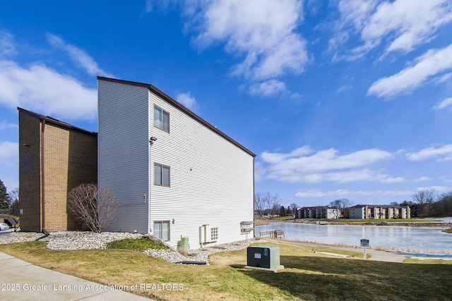 view of home's exterior with a yard and a water view