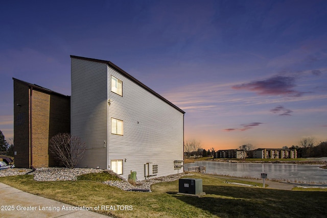 property exterior at dusk featuring a yard