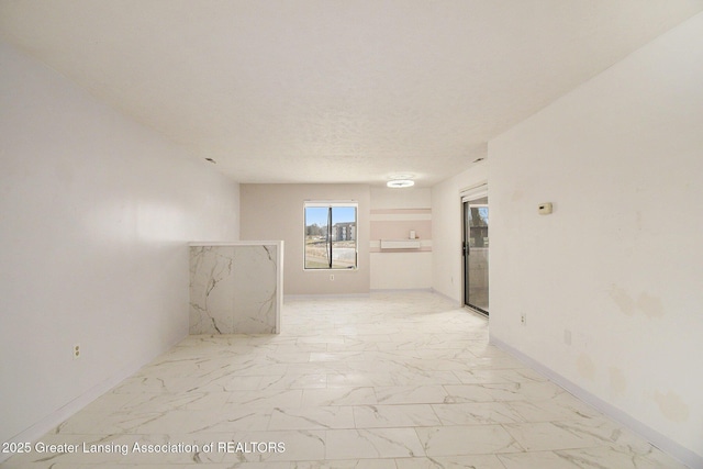 unfurnished room featuring baseboards, a textured ceiling, and marble finish floor