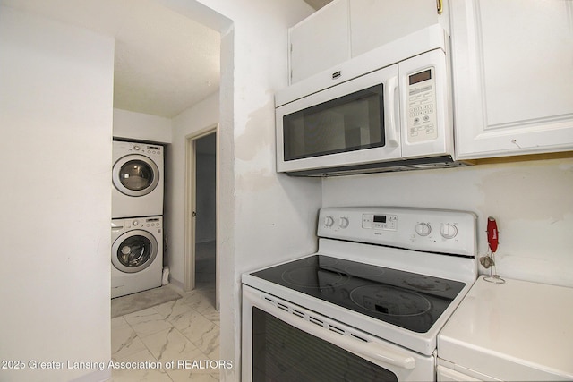 kitchen with white appliances, stacked washing maching and dryer, light countertops, white cabinetry, and marble finish floor