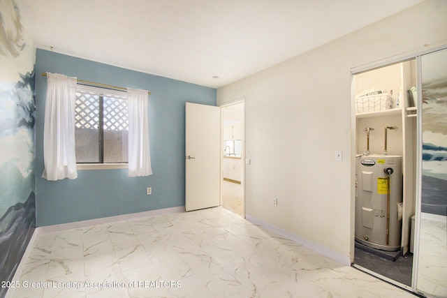 bedroom featuring a closet, marble finish floor, electric water heater, and baseboards