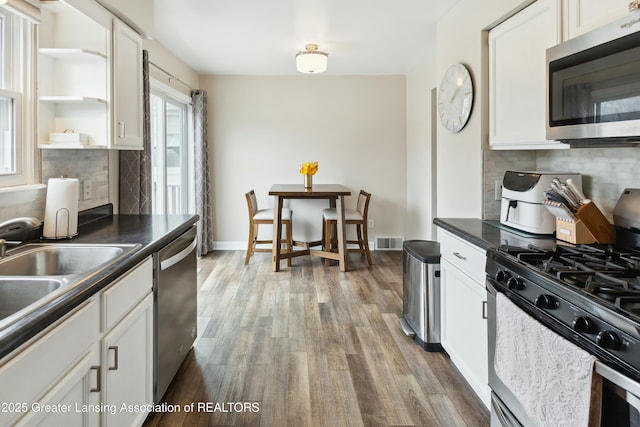 kitchen with visible vents, dark countertops, wood finished floors, white cabinetry, and stainless steel appliances