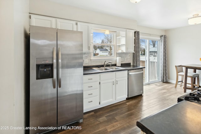 kitchen with dark countertops, appliances with stainless steel finishes, white cabinetry, and a sink