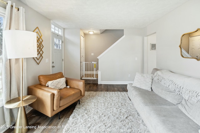 living room featuring baseboards, dark wood-style floors, and stairs