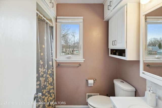 full bath with vanity, toilet, a shower with curtain, and visible vents