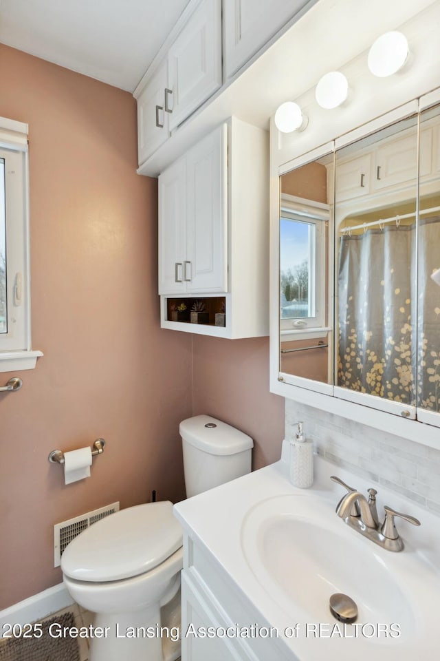 bathroom featuring visible vents, baseboards, toilet, a shower with curtain, and vanity