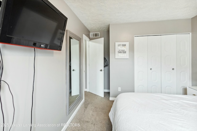 carpeted bedroom featuring a closet, visible vents, a textured ceiling, and baseboards