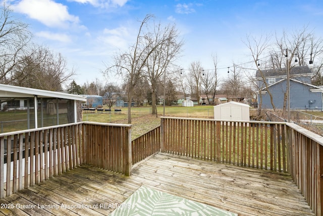 wooden deck featuring an outbuilding, a yard, a residential view, and a shed