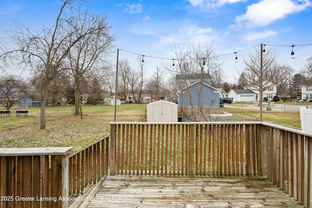 deck featuring a storage unit, a residential view, an outbuilding, and a lawn