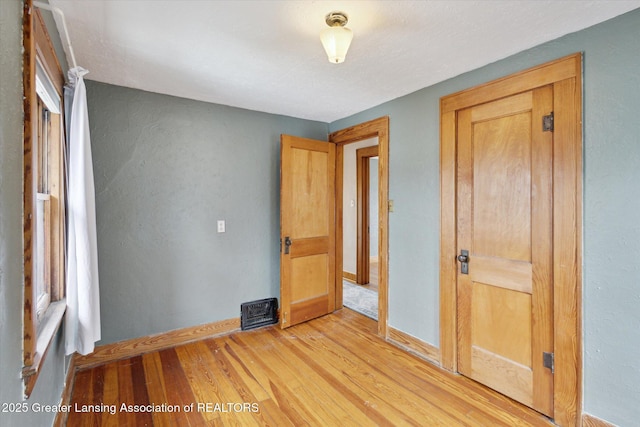 unfurnished bedroom featuring visible vents, light wood-type flooring, and baseboards