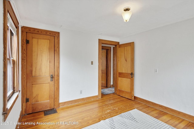 unfurnished bedroom featuring light wood finished floors, visible vents, and baseboards