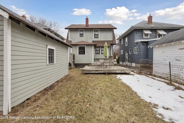 rear view of house with a lawn, a wooden deck, and fence