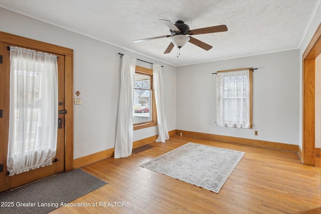 entrance foyer featuring light wood-style floors, ornamental molding, and a textured ceiling