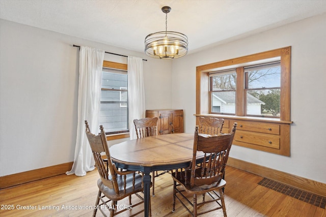 dining room with visible vents, baseboards, light wood-style floors, and a notable chandelier